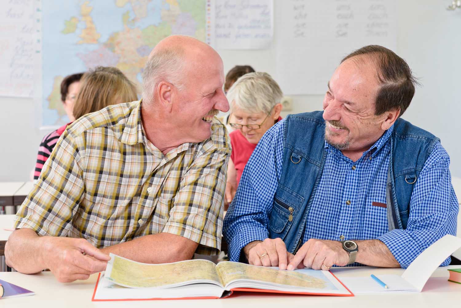 Zwei ältere Herren mit Atlas lachen